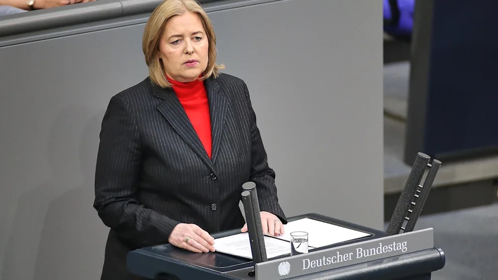Bärbel Bas in a dark pinstripe suit and red roll-neck speaking at the lectern marked Deutscher Bundestag