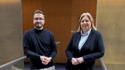 Bärbel Bas standing beside a young man in glasses and a dark jumper on a stairway in a Bundestag building