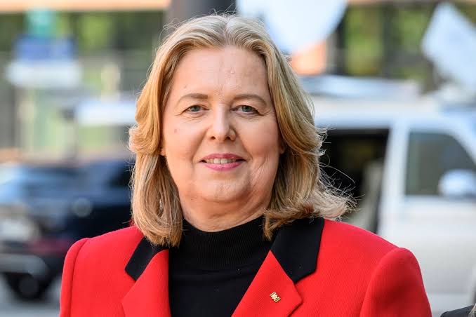 Bärbel Bas smiling in a red jacket with a black collar, photographed outdoors