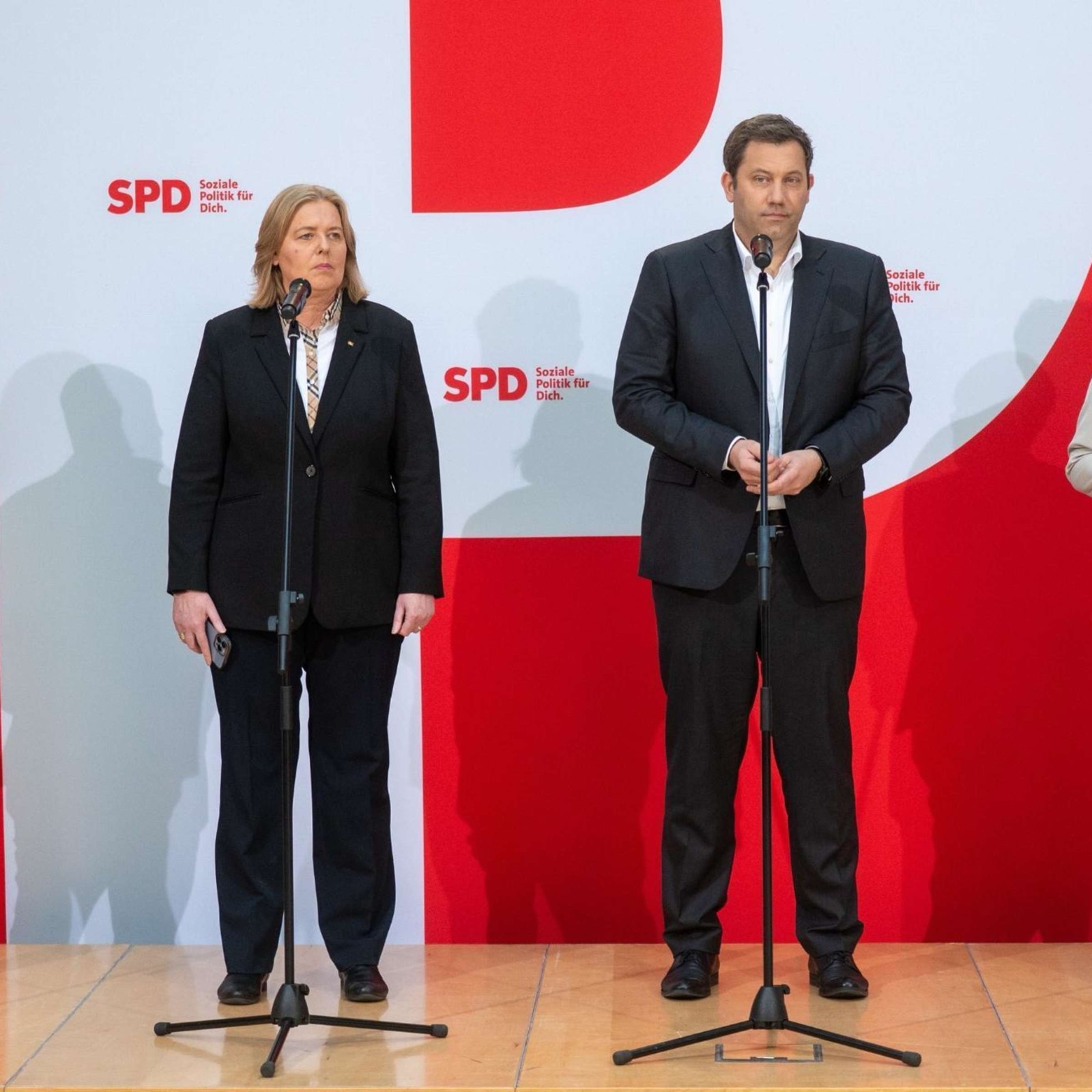 Bärbel Bas and Lars Klingbeil standing at microphones in front of an SPD backdrop at a press conference