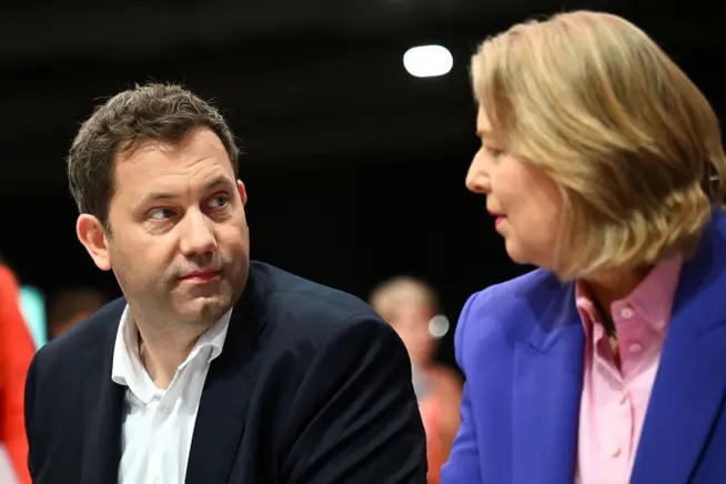 Lars Klingbeil and Bärbel Bas seated next to each other at a party event, looking at each other