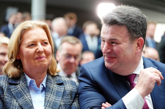 Bärbel Bas and Hubertus Heil seated side by side at an event, smiling at each other